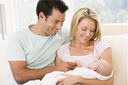 Ehepaar betrachtet freudig ihr neugeborenes Kind