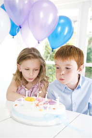 Kind bläst Kerzen auf einer Torte aus
