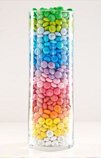 Ein Glas gefüllt mit Schokolinsen in verschiedenfarbenen Schichten